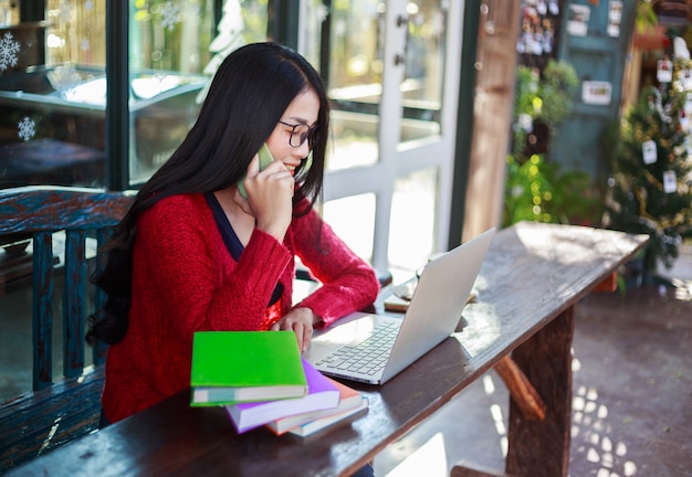 Mulher que trabalha com laptop e ligar com o celular no café