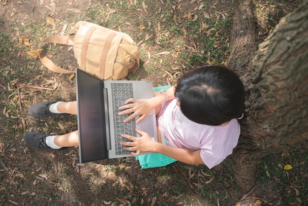 Mulher que trabalha com notebook portátil na floresta