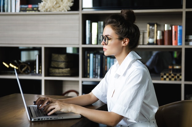 Mulher que trabalha com o laptop em seu escritório