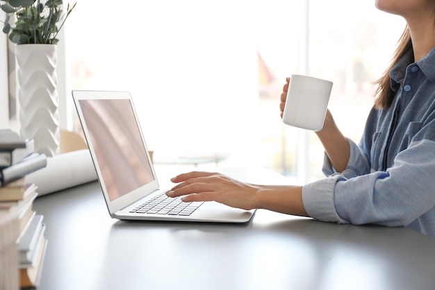 Mulher que trabalha em um escritório confortável com laptop