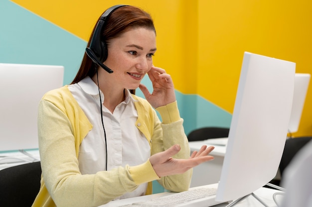 Mulher que trabalha no escritório de call center com fones de ouvido e computador