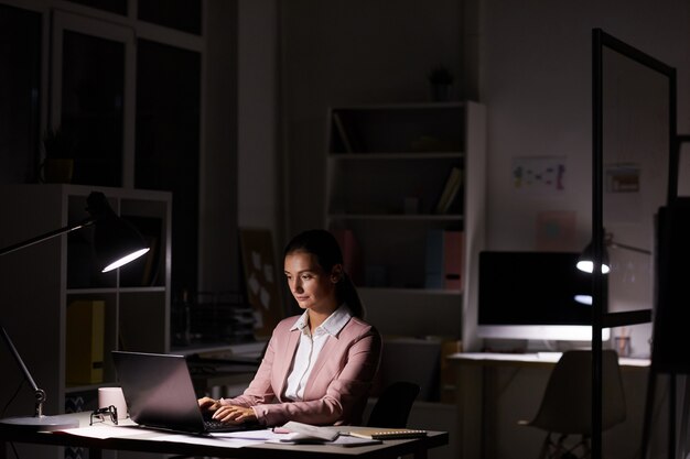 Foto mulher que trabalha no escritório escuro