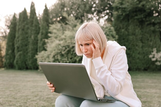 Mulher que trabalha no parque com telefone e laptop Empresária trabalha fundo de natureza verde ao ar livre Conexão de rede Wi fi acesso gratuito Freelancer relaxando na natureza e usando tecnologia