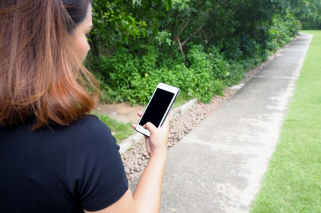 Foto mulher que usa o telefone no jardim