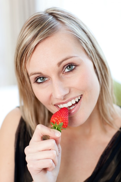 Mulher radiante comendo um morango