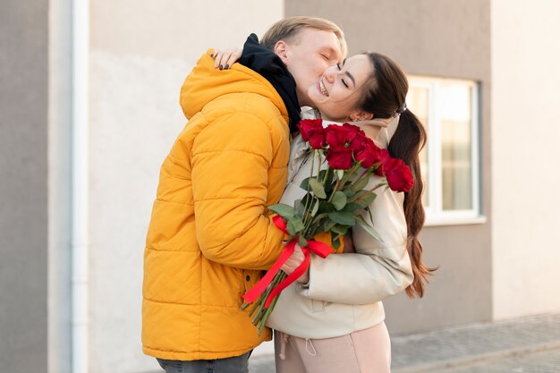 Foto mulher recebendo buquê de rosas vermelhas do namorado no dia dos namorados ao ar livre