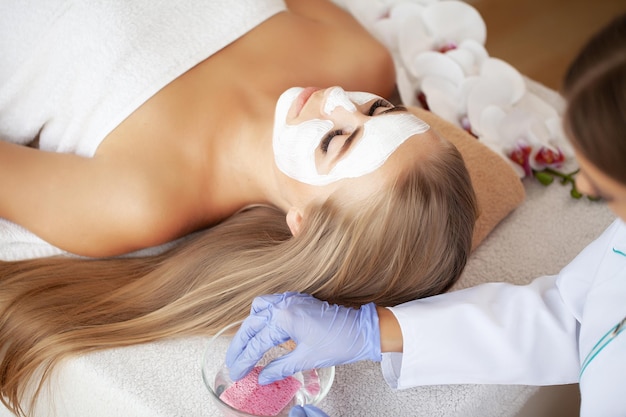 Mulher recebendo cuidados faciais por esteticista no salão spa