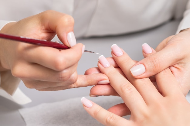 Mulher recebendo manicure francesa por esteticista