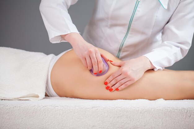 Mulher recebendo massagem anticelulite da perna com uso de latas de vácuo
