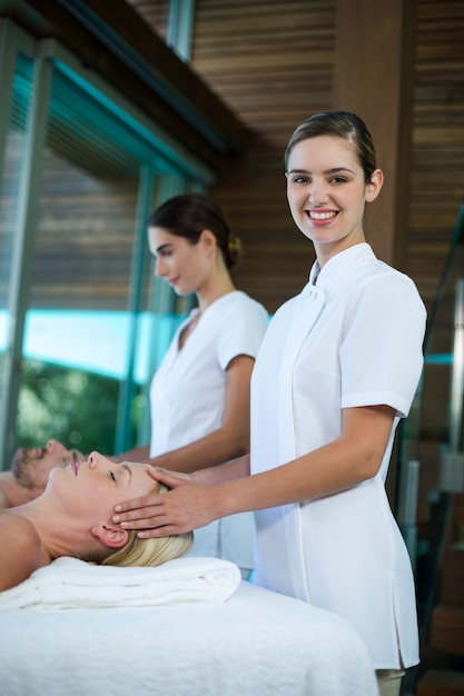 Mulher recebendo massagem na cabeça do massagista