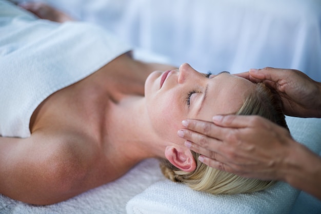 Mulher recebendo massagem na cabeça do massagista