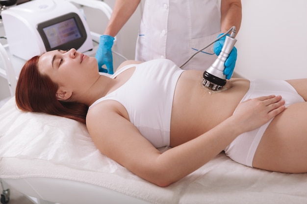 Mulher recebendo tratamento de cosmetologia corporal em clínica de beleza
