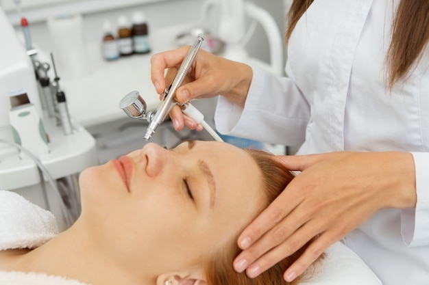 Mulher recebendo tratamento facial na clínica de dermatologia