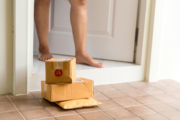 Mulher recolhe o pacote na caixa da porta perto da porta no chão Caixas de compras online entregues à sua porta Fácil de roubar quando ninguém está em casa Pacote em caixa de papelão à porta Serviço de entrega