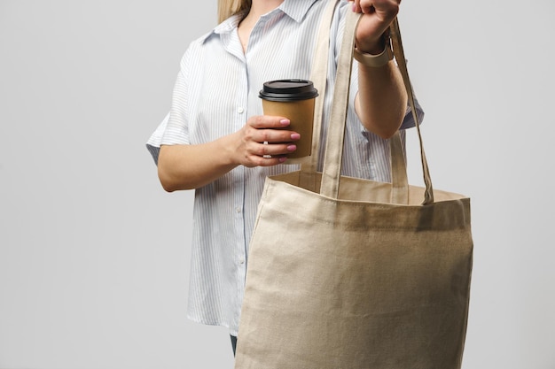 Mulher recortada com saco de algodão e xícara de café de papel studio shot