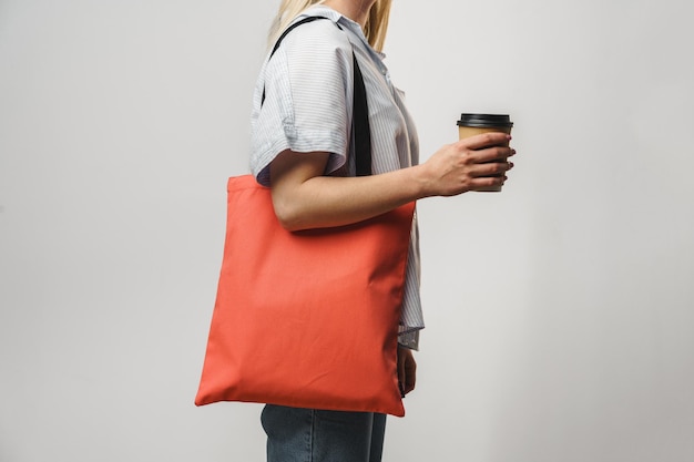 Mulher recortada com saco de algodão e xícara de café de papel studio shot