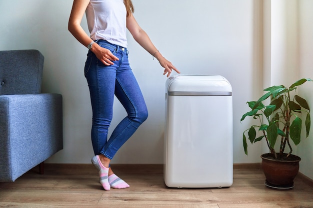 Mulher regula a temperatura de resfriamento do ar condicionado no clima quente de verão. ar fresco e limpo em casa