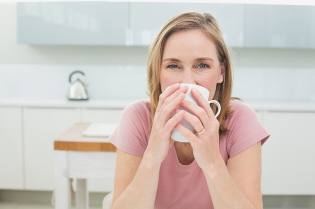 Mulher relaxada com café na cozinha