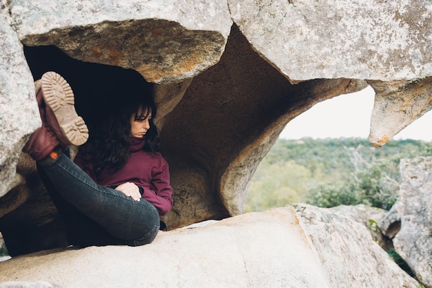 Mulher relaxada deitada em uma caverna enquanto olha a paisagem