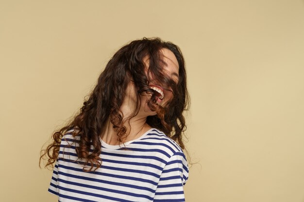 Foto mulher relaxada e despreocupada brincando com cabelo castanho cacheado, olhos fechados, mulher, curtindo um penteado saudável