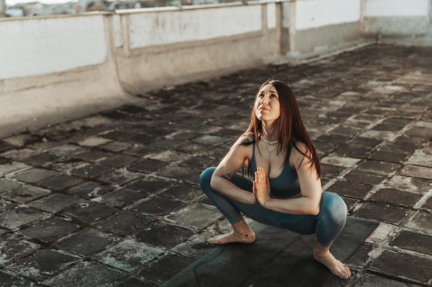 Mulher relaxada praticando exercícios de alongamento de ioga em um terraço.