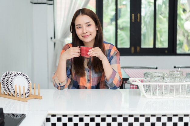 Mulher relaxada tomando café na cozinha