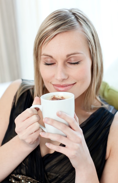 Mulher relaxada tomando um café sentado em um sofá