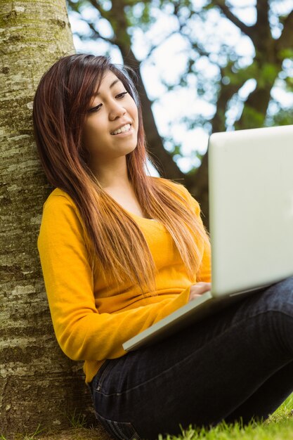 Mulher relaxada usando laptop no parque