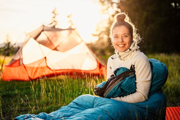 Mulher relaxando e deitada em um saco de dormir na barraca Sunset acampando na floresta Montanhas paisagem viagem estilo de vida camping Viagem de verão aventura ao ar livre