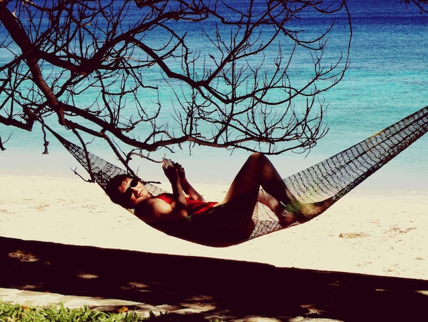 Foto mulher relaxando em uma hamaca na praia