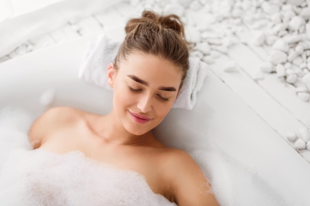 Mulher relaxando na banheira com espuma de sabão