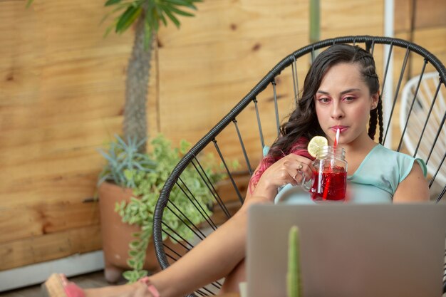 Mulher relaxando nas férias de verão e bebendo um coquetel enquanto trabalha