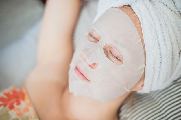 Mulher relaxante na cama com uma máscara facial