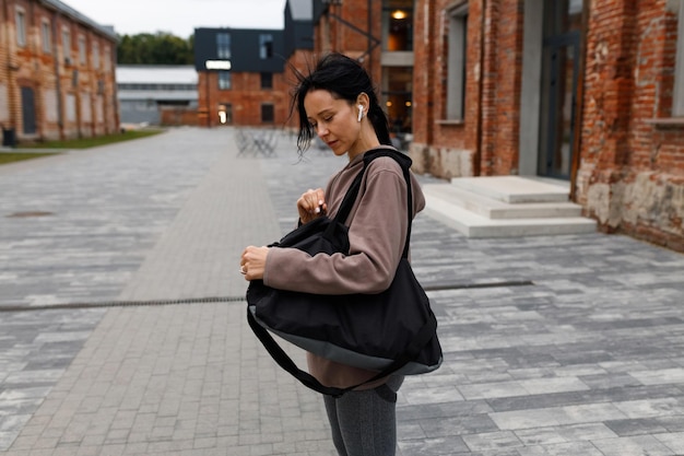 Mulher remexe em sua bolsa de ginástica depois de malhar na academia