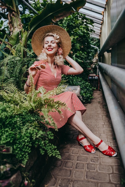 Mulher retrô e vintage elegante no jardim cheio de flores e plantas tropicais