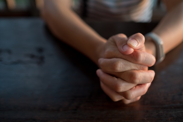 mulher rezando de manhã, as mãos postas em oração