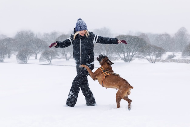 Mulher rindo brinca com cão boxer em winter park. Amor e amizade.