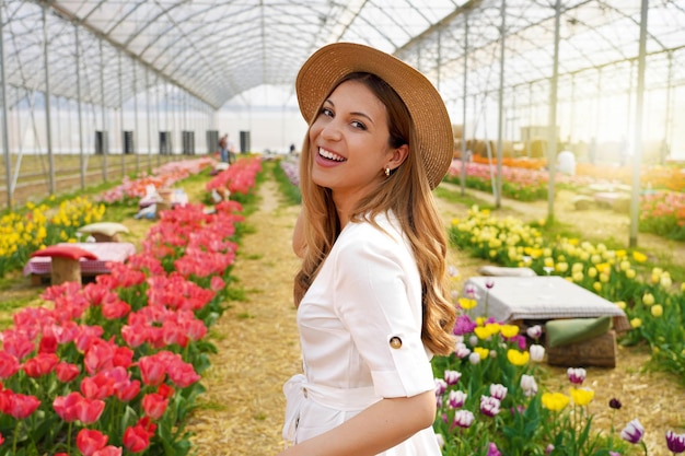 Mulher rindo se vira e olha para a câmera andando entre tulipas e mesas de piquenique