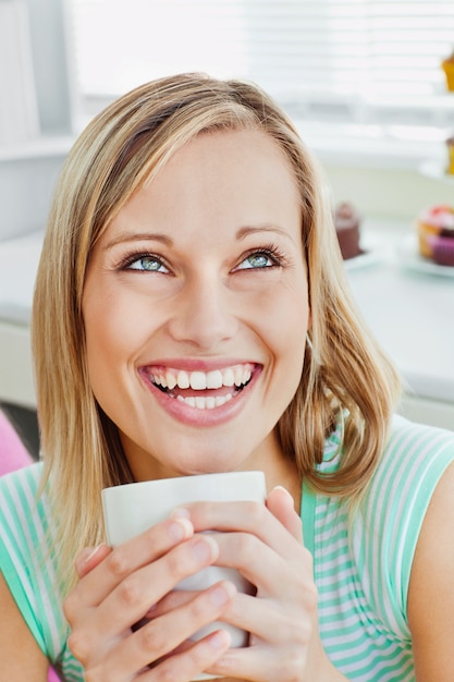 Mulher rindo segurando uma xícara de café em casa