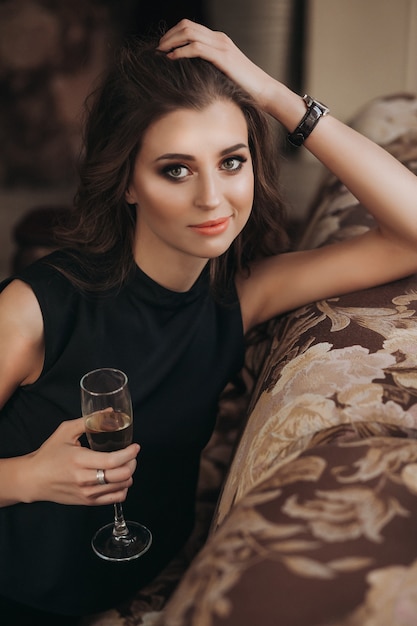 Mulher romântica e triste com cabelo comprido segurando uma taça de champanhe. Cabelo lindo, longo e saudável.