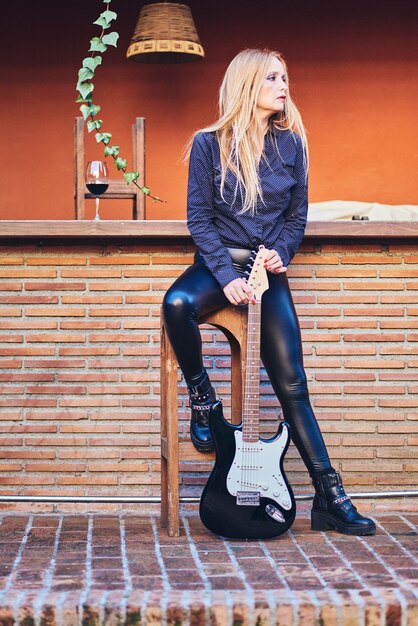 Mulher roqueira posando com uma guitarra.