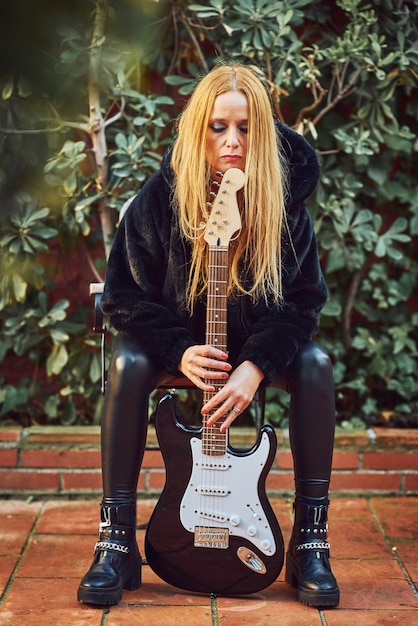 Mulher roqueira posando com uma guitarra.