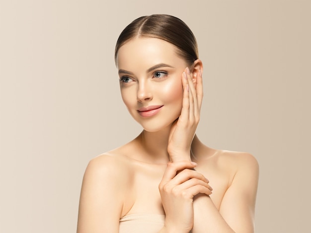 Foto mulher rosto beleza mão tocando rosto saudável maquiagem natural feminino fundo bege