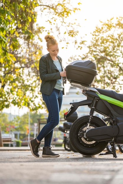 Mulher ruiva abrindo o porta-malas de sua motocicleta estacionada