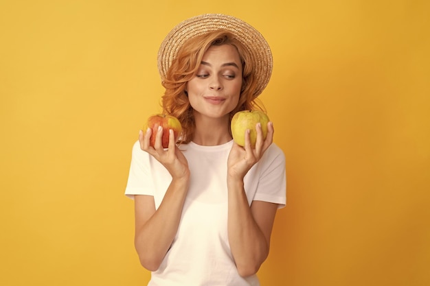 Mulher ruiva bonita com chapéu de palha segura a saúde da maçã