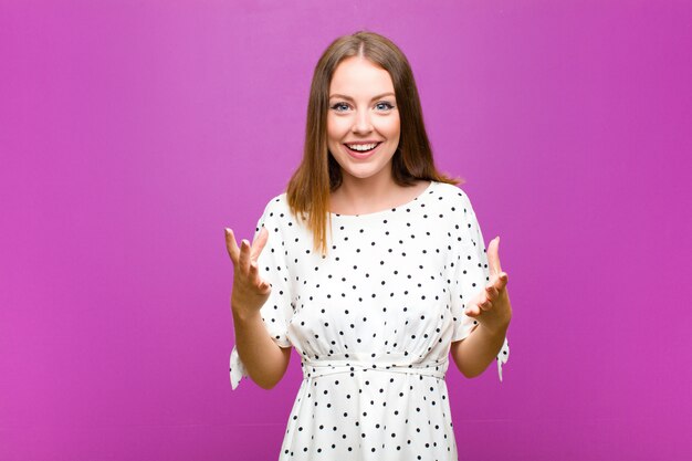 Mulher ruiva bonita se sentindo feliz, atônita, sortuda e surpresa, como dizer omg a sério? Inacreditável contra a parede roxa