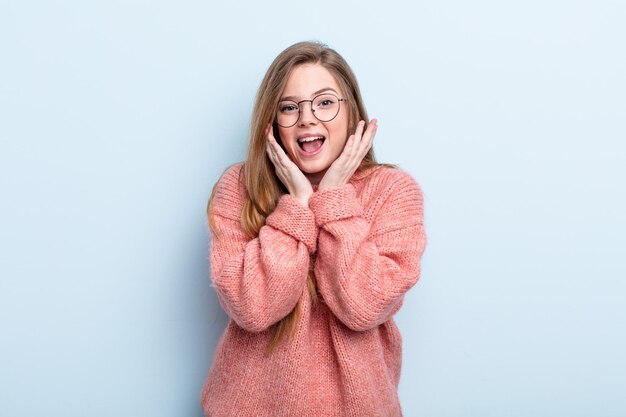 Mulher ruiva caucasiana se sentindo chocada e animada rindo espantada e feliz por causa de uma surpresa inesperada