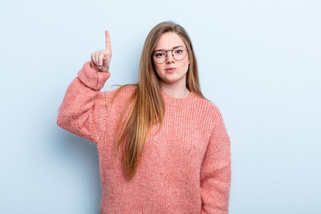 Mulher ruiva caucasiana se sentindo um gênio segurando o dedo orgulhosamente no ar depois de perceber uma ótima ideia dizendo eureka