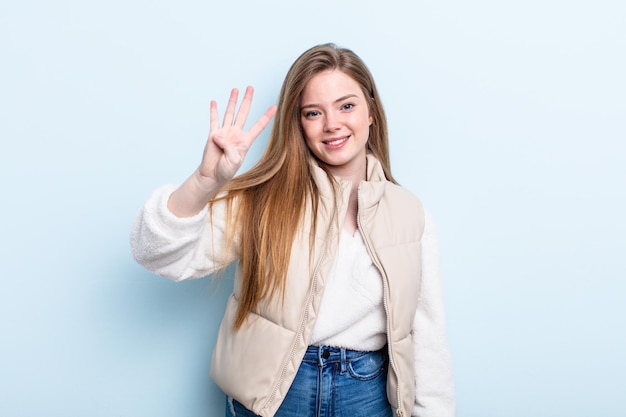 Mulher ruiva caucasiana sorrindo e parecendo amigável mostrando o número quatro ou quarto com a mão em contagem regressiva