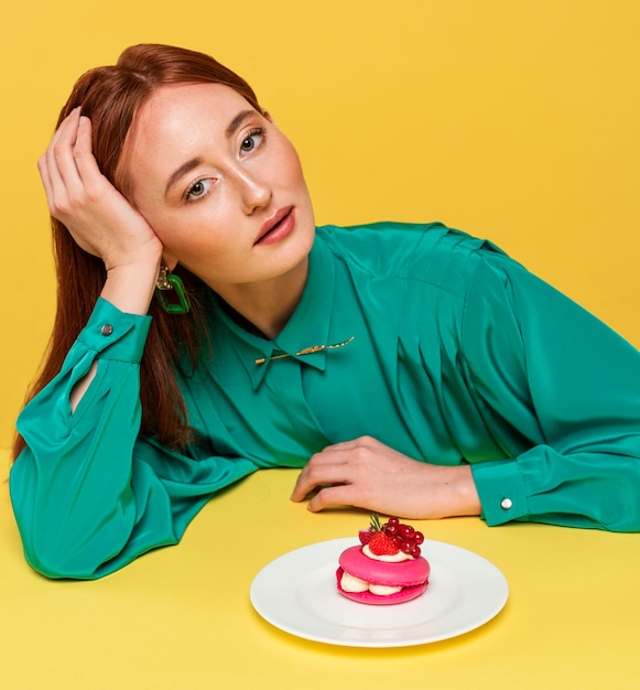 Foto mulher ruiva com blusa verde mostrando um bolo delicioso
